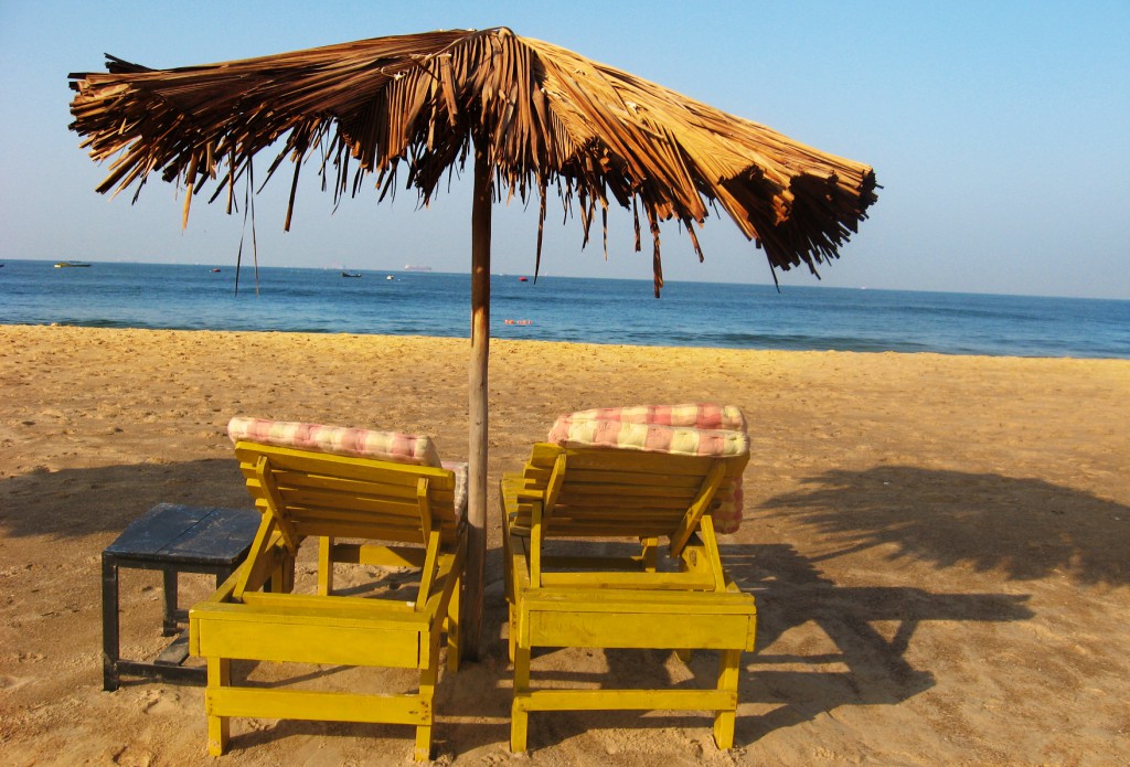 Two chairs under a thatch umbrella on a beach