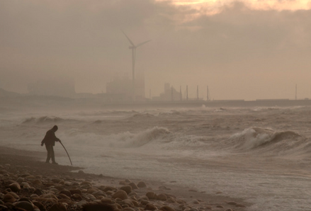 Person standing on a beach in a storm. Photo by Witch Kiki, Unsplash.