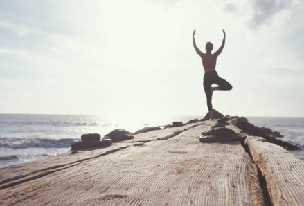 Person doing yoga on a wooden walkway. Photo by Marion Michele, Unsplash.