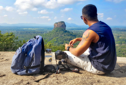 Man sitting on a mountaintop with a backpack.